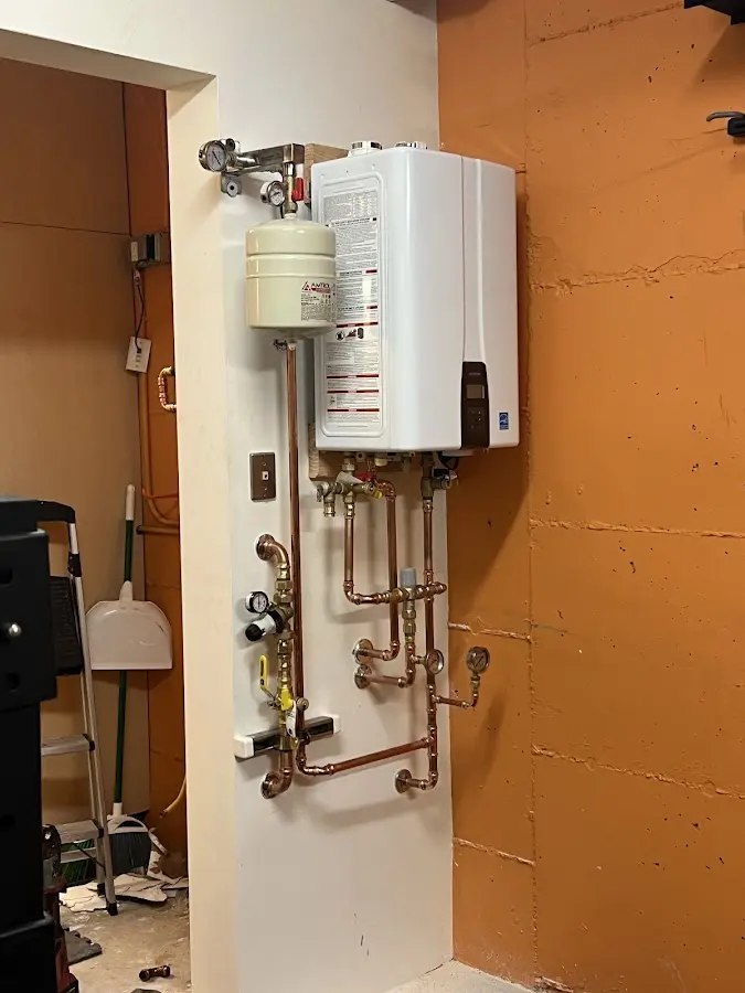 Plumbing technician inspecting water heater connections in Caroline